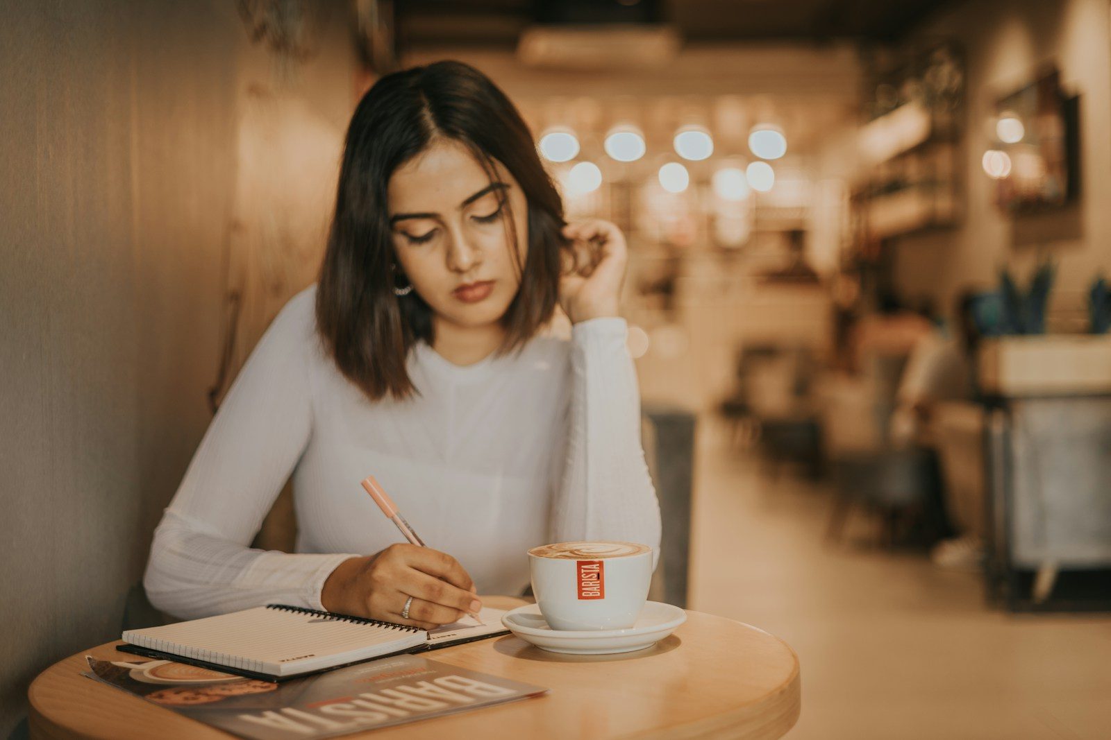 A woman writing in a notebook at a café table